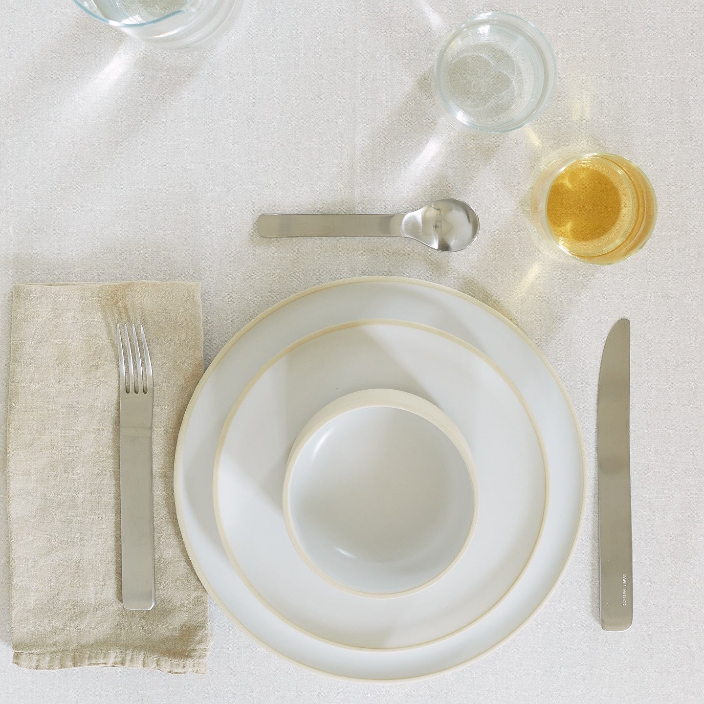 Placesetting with Modernist Dinnerware on white tablecloth.