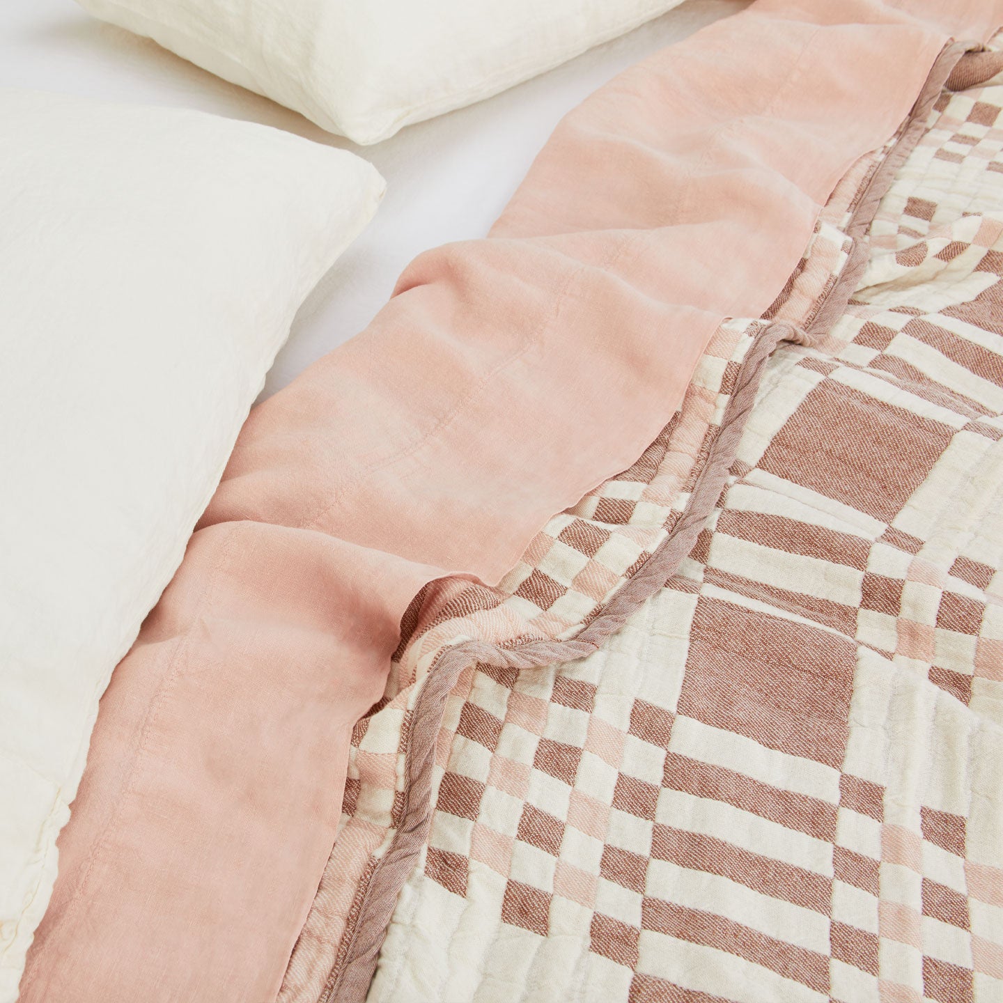 Simple Plaid Blanket in Blush and Terracotta on a bed with white, ivory, and blush pillows and sheets.