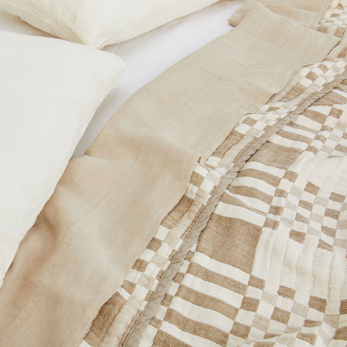 Simple Plaid Blanket in Ivory and Flax on a bed with white, ivory, and flax pillows and sheets.