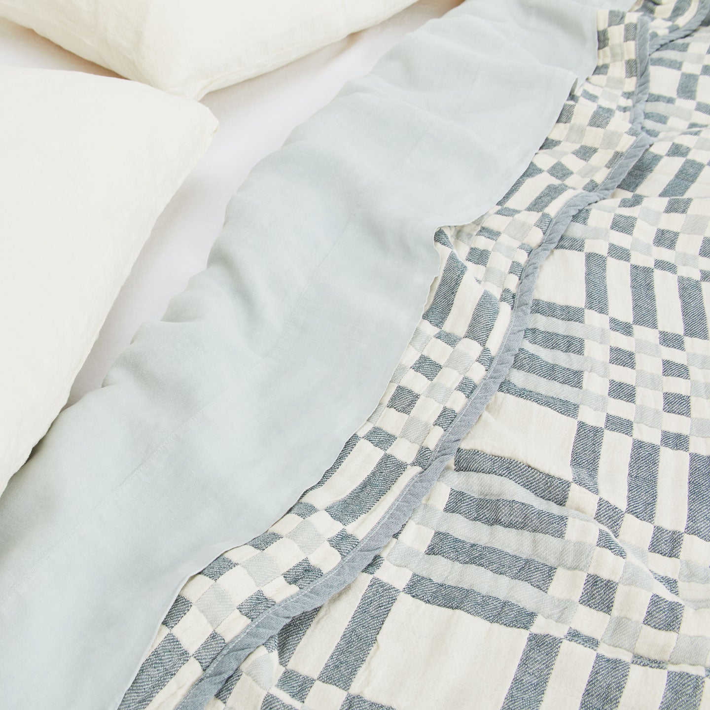 Simple Plaid Blanket in Sky and Peacock on a bed with white, ivory, and sky pillows and sheets.