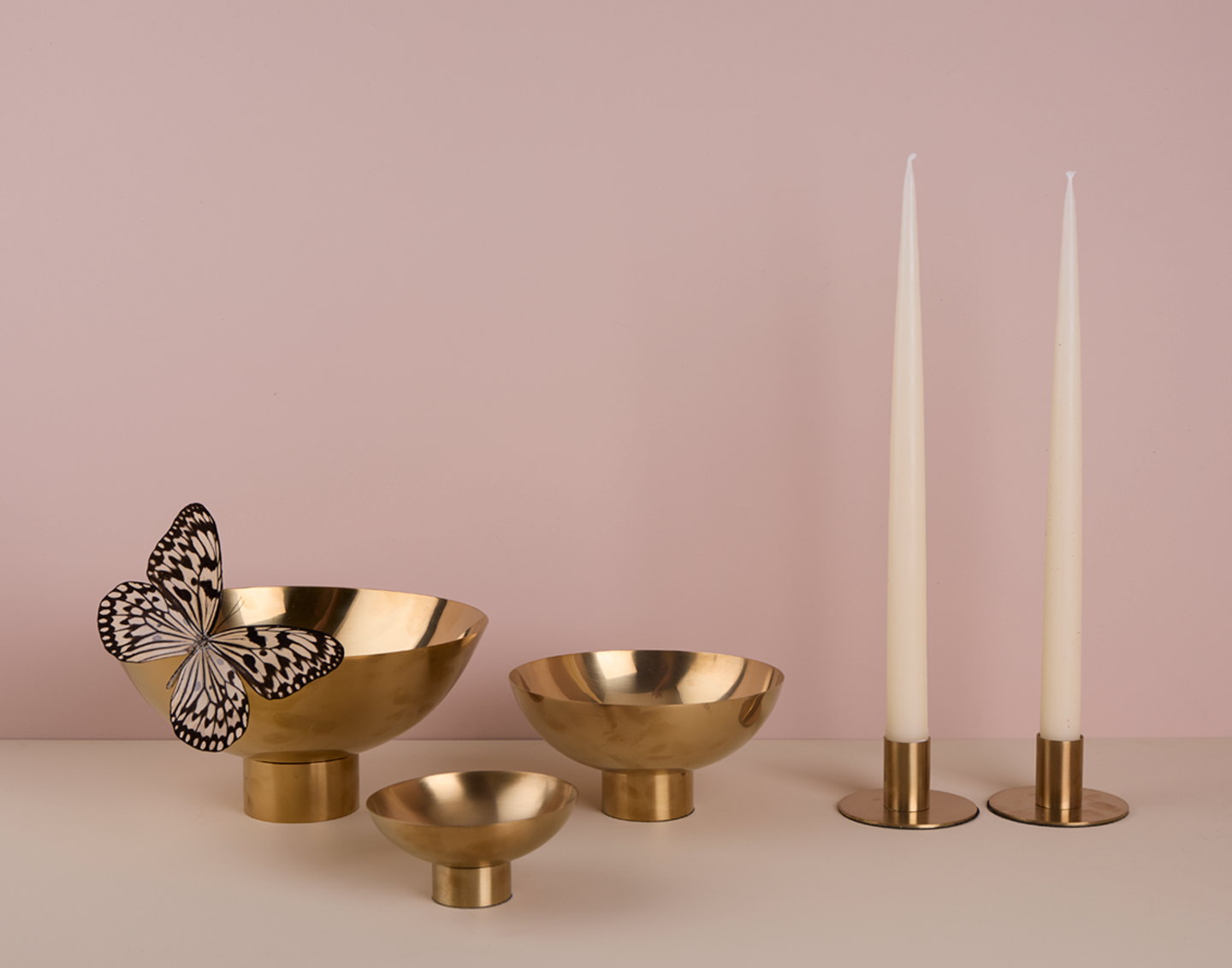 Footed brass bowls with butterfly, and brass taper holders with white taper candles