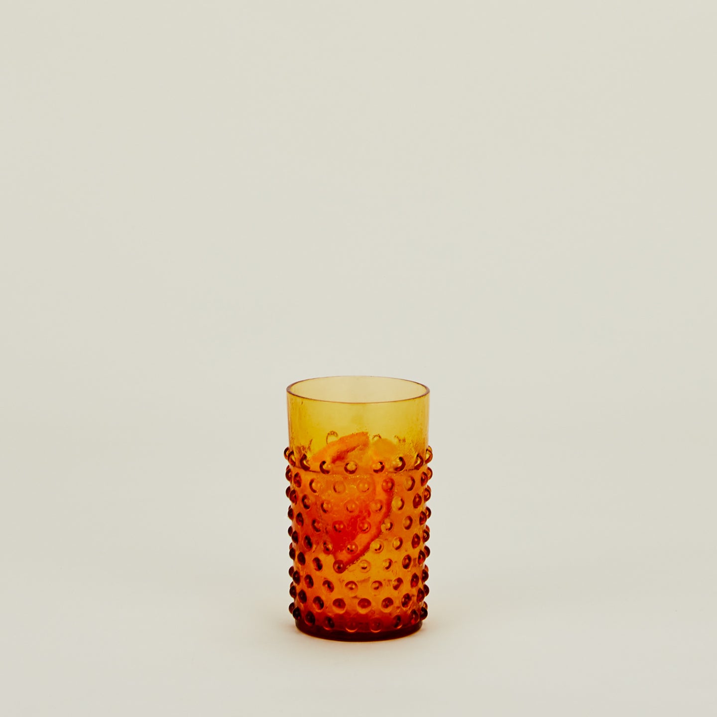 Hobnail Tumbler in Amber filled with water and fruit.