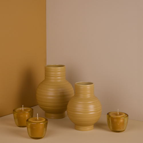 A pair of ceramic vases and trio of glass votive holders with votive candles. All in Mustard tones.