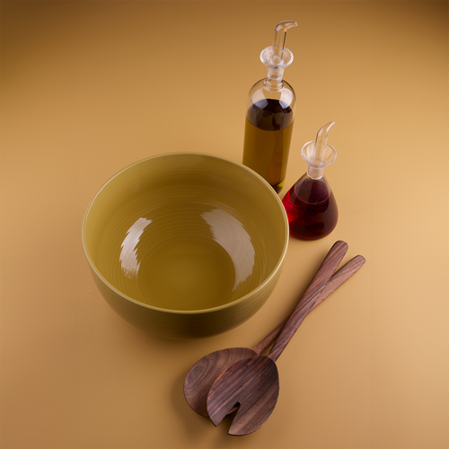 Essential Serving Bowl in Mustard, alongside walnut wood serving set and glass oil and vinegar bottles.