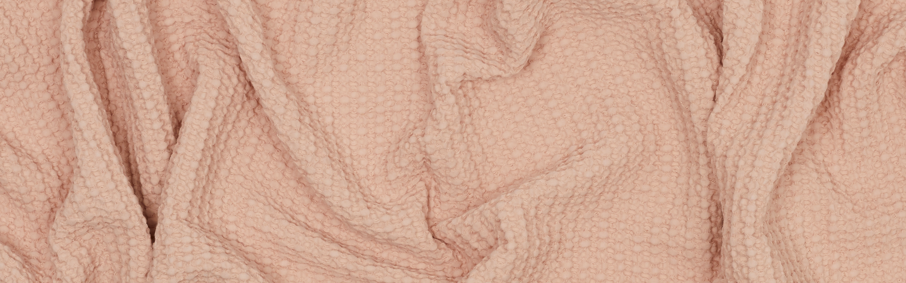 Detail of the texture of a waffle towel in blush color.