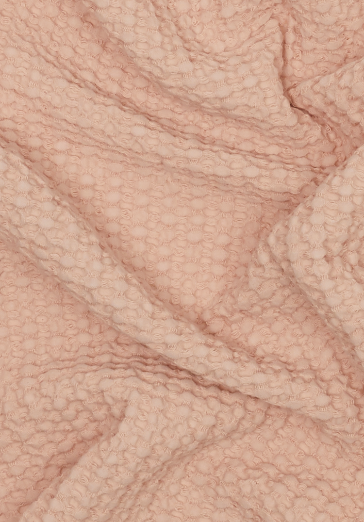 Detail of the texture of a waffle towel in blush color.