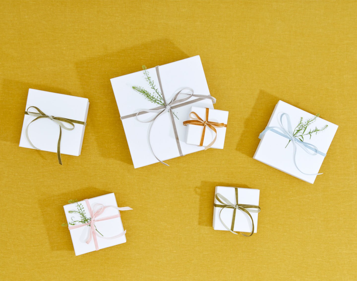 Group of gift packages wrapped in white paper and tied with thin velvet ribbon.