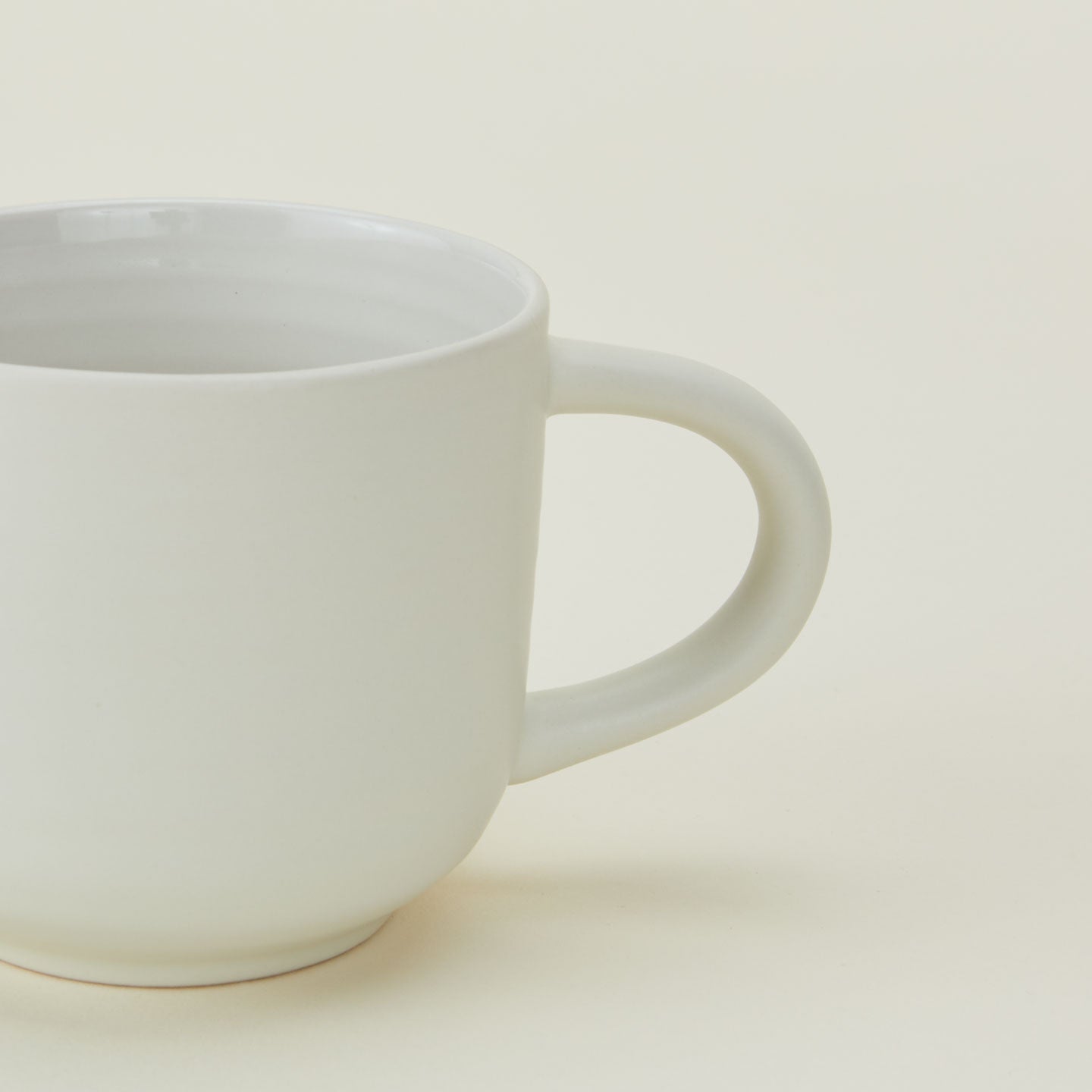 A white ceramic mug with a handle, positioned against a light background.