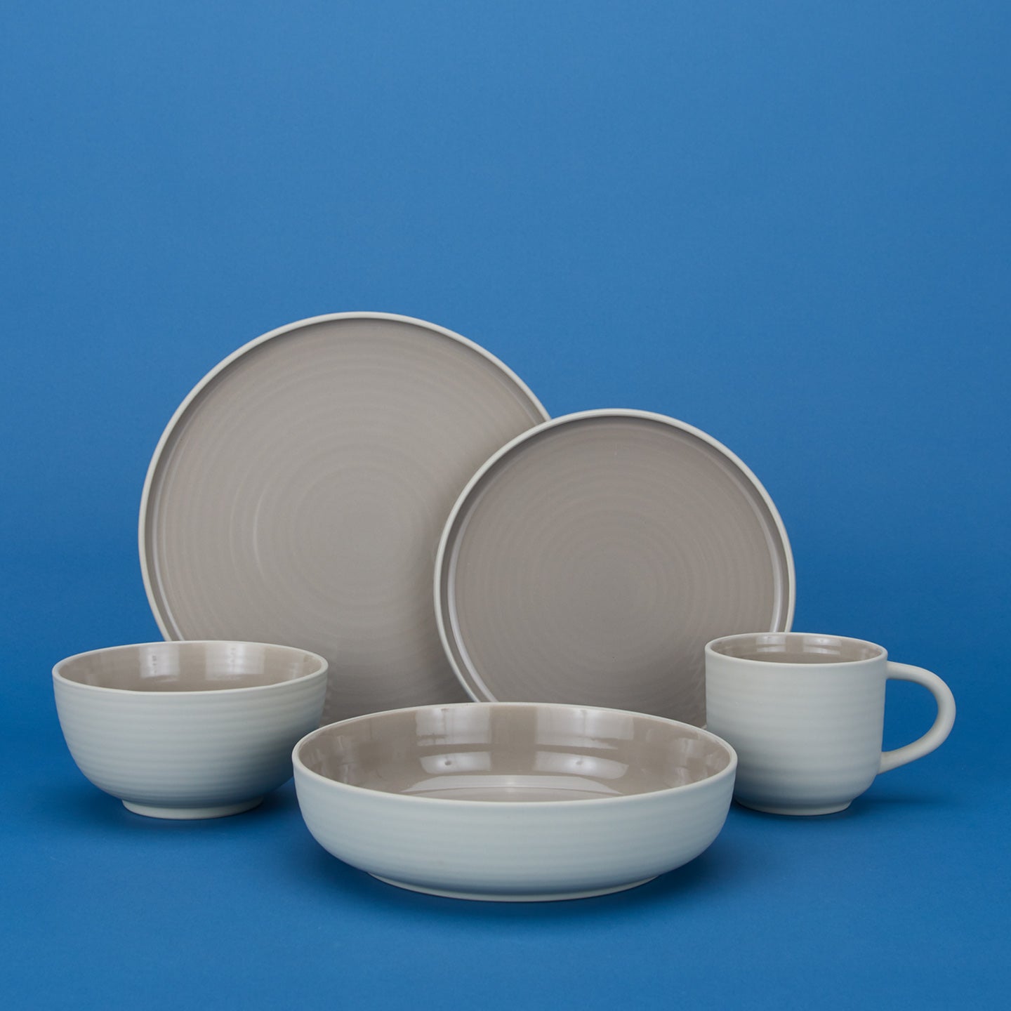 Group of Essential Dinnerware in Light Grey including low bowl, large bowl, salad plate, dinner plate and mug.