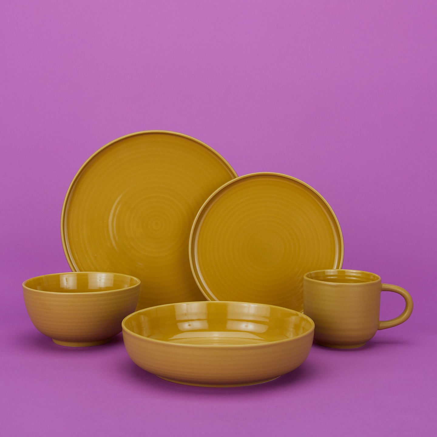 Group of Essential Dinnerware in Mustard including low bowl, large bowl, salad plate, dinner plate and mug.