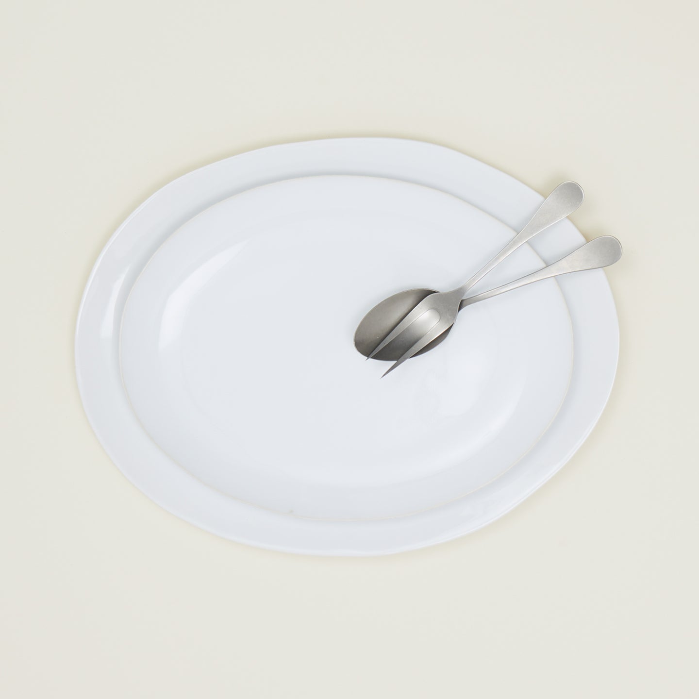 White Strata Serving Platter in two sizes stacked, with serving spoon.