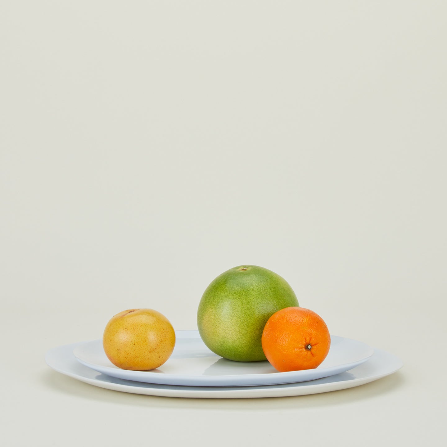 White Strata Serving Platter in two sizes stacked, with citrus fruit.