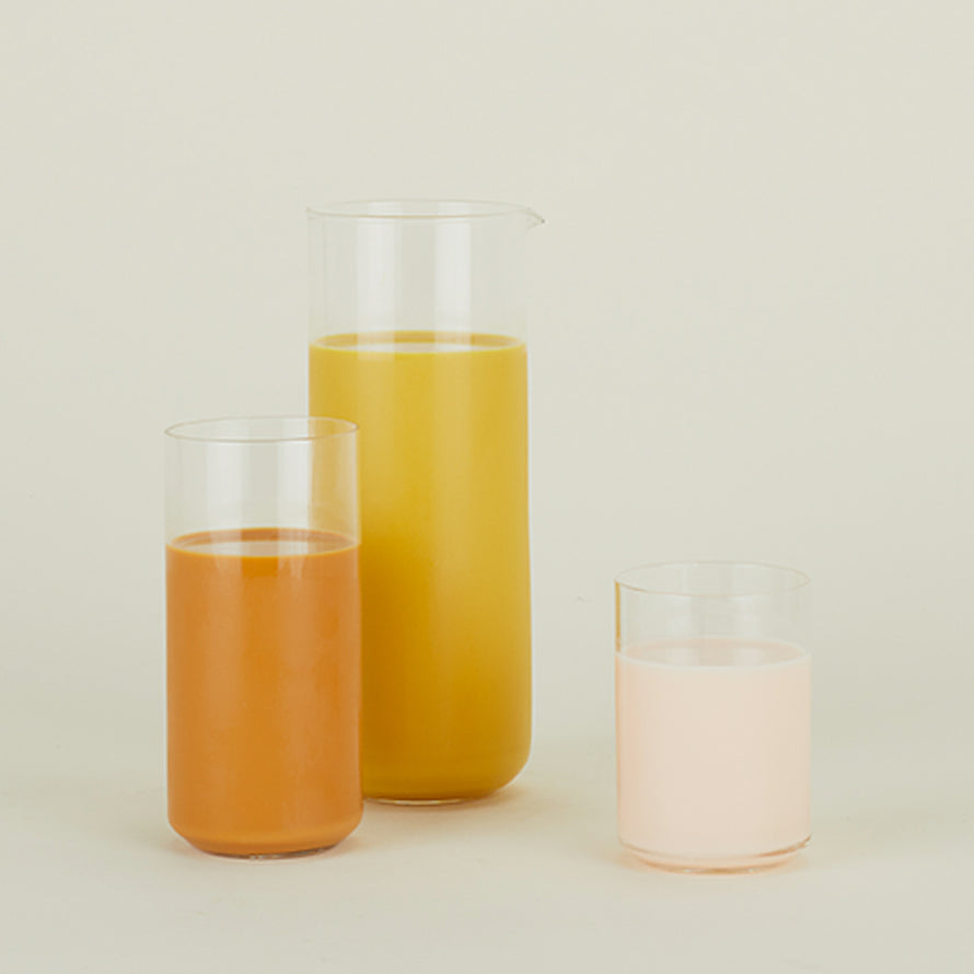 Simple Glass Pitcher and two Simple Glass Tumblers filled with orange liquids.