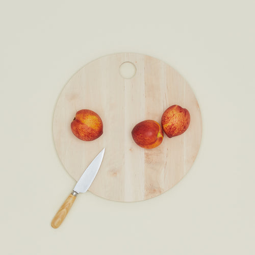 Iris Hantverk birch round cutting board with peaches and knife