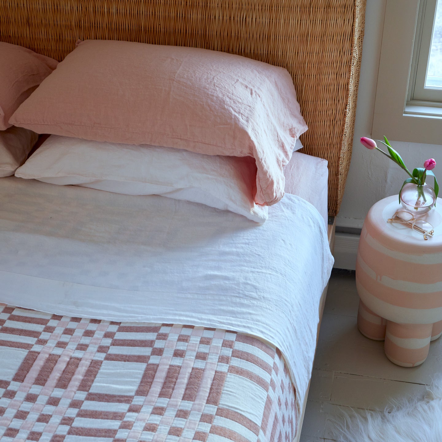 Simple Plaid Blanket in Blush and Terracotta on a bed with white and blush pillows and sheets.