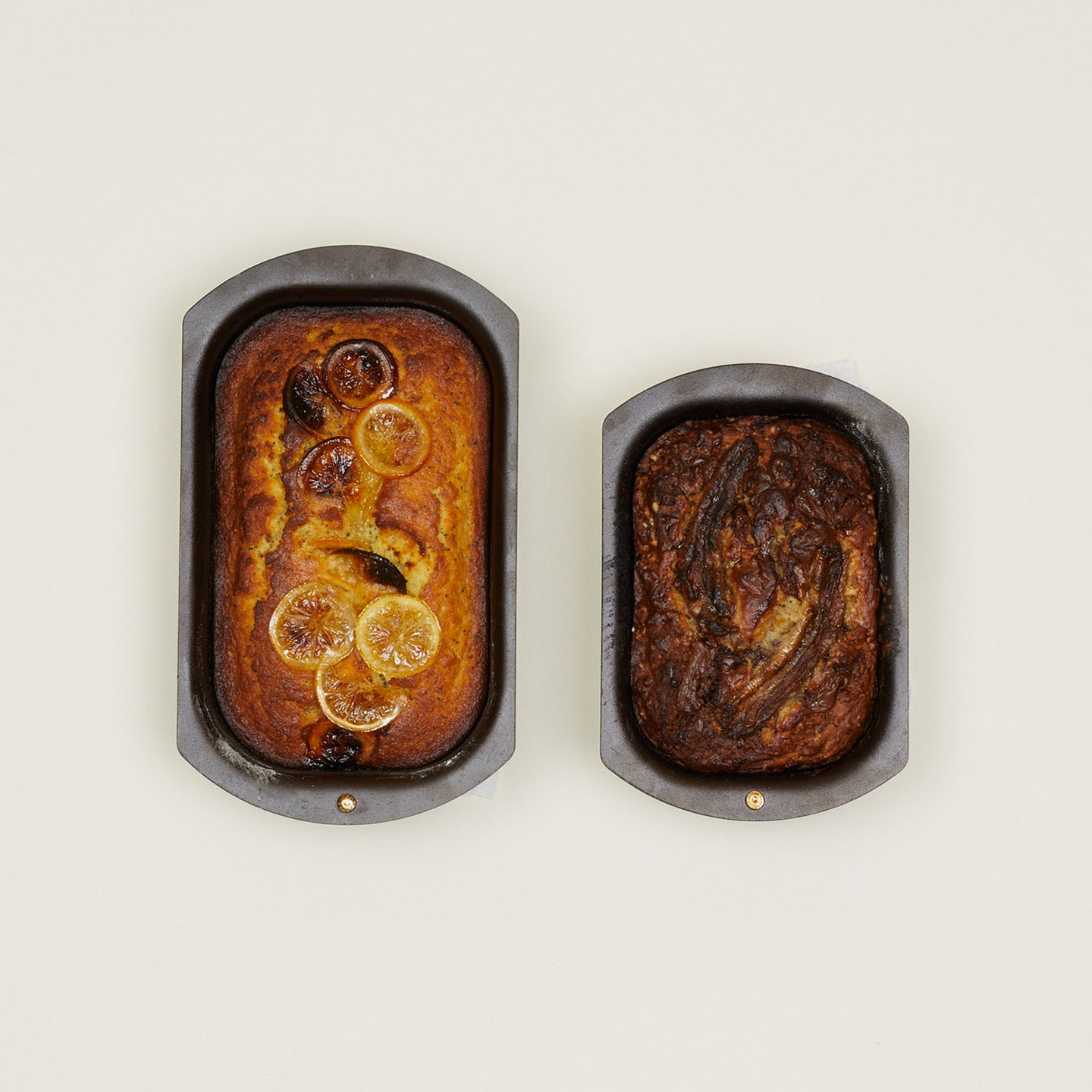 Overhead view of lare and small spun iron loaf pans with cake and bread