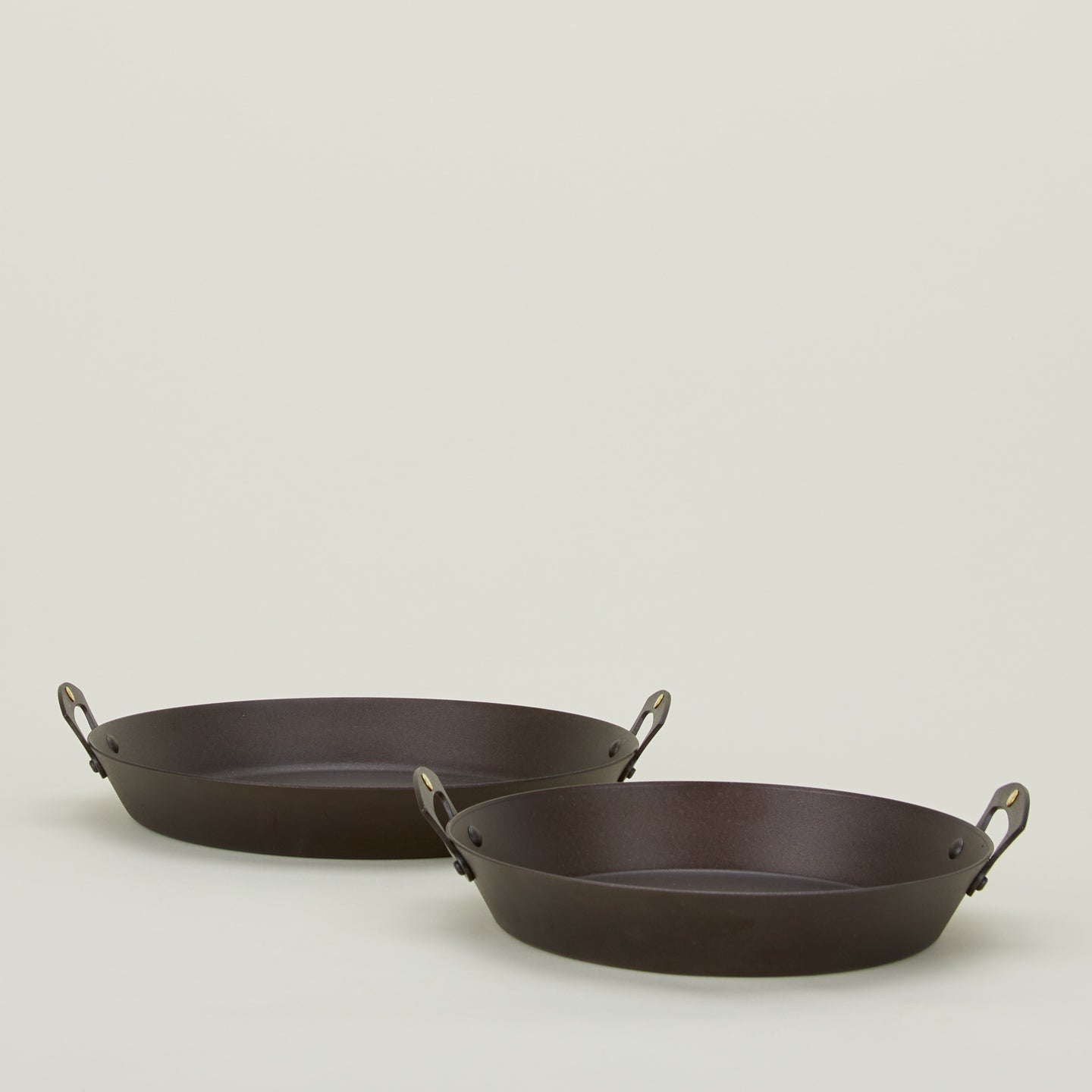 Large and small spun iron two handled saute pans