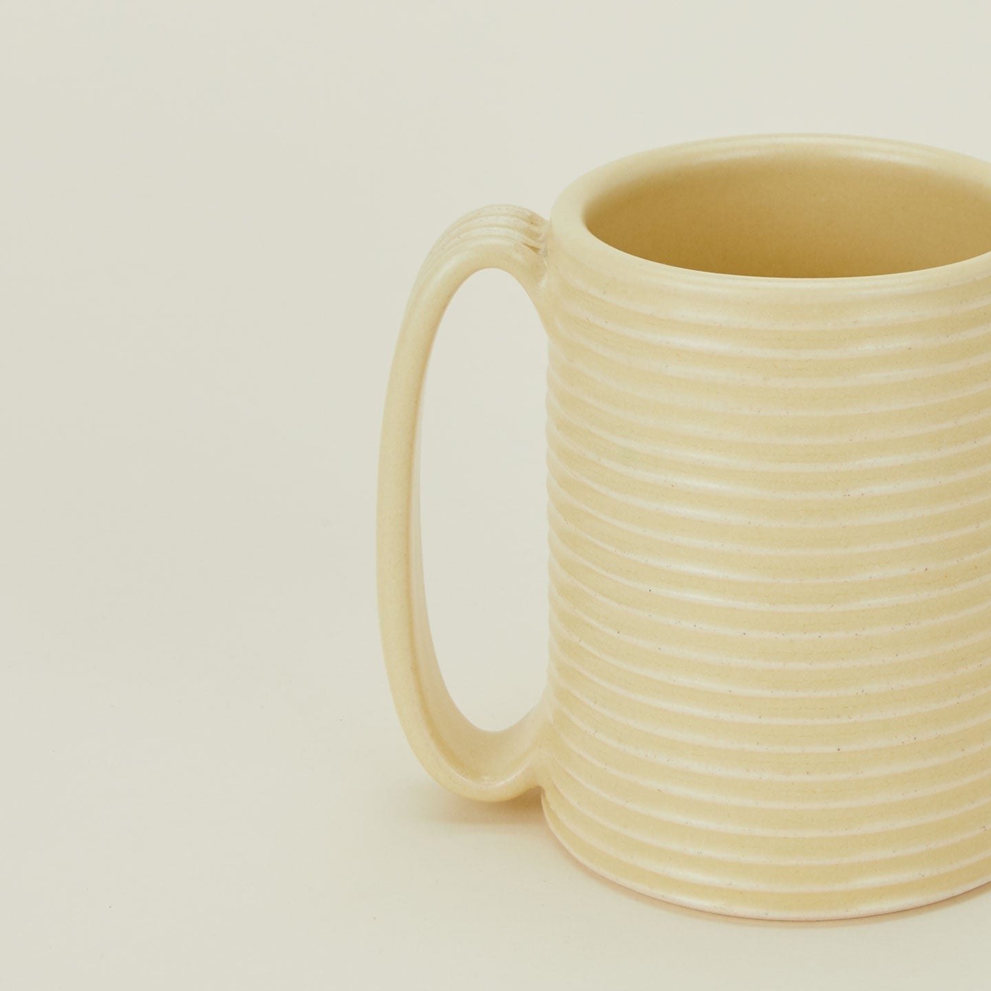 Close up of a Tall Ribbed Mug in Butter.