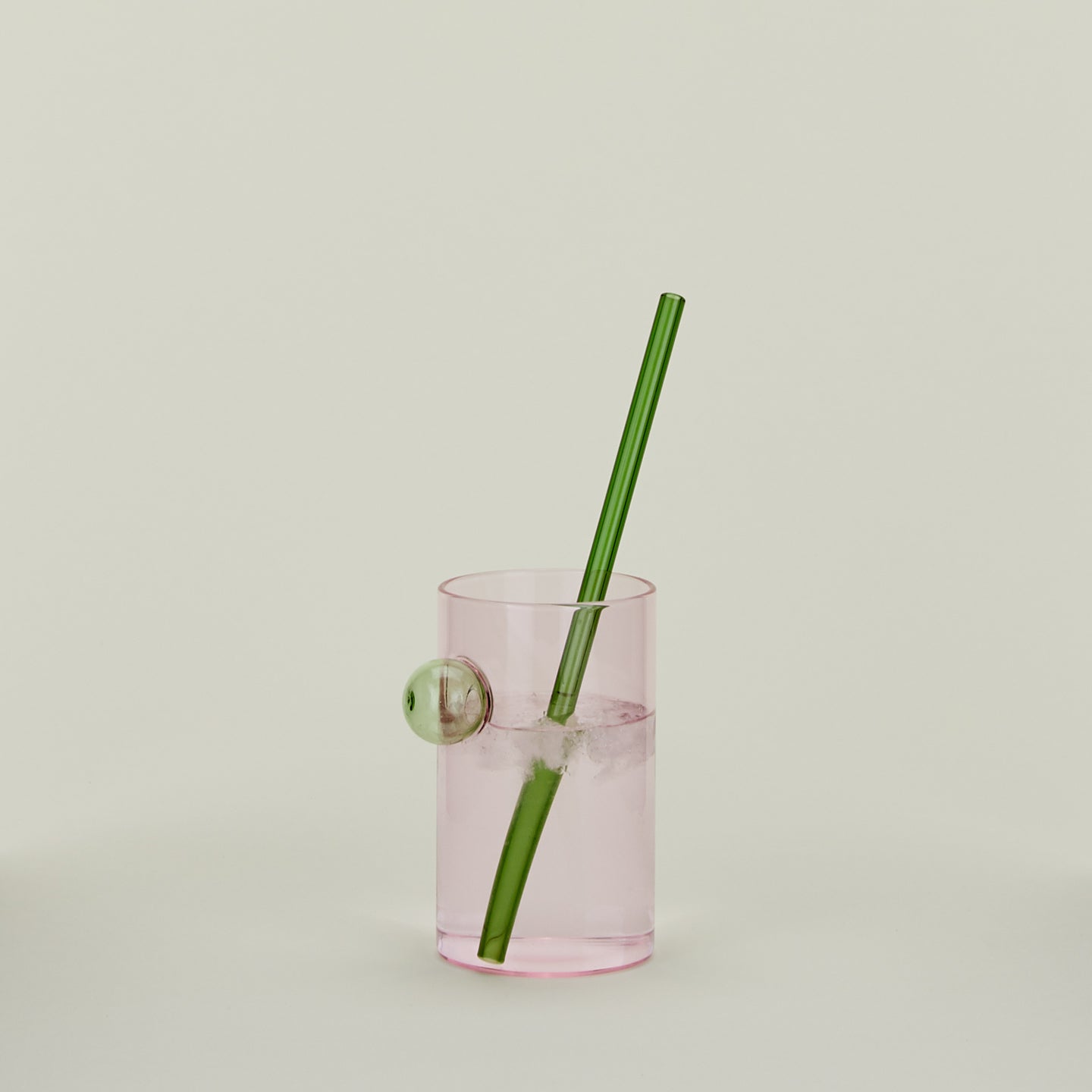 Bubble Glass in Blush with straw, filled with water.