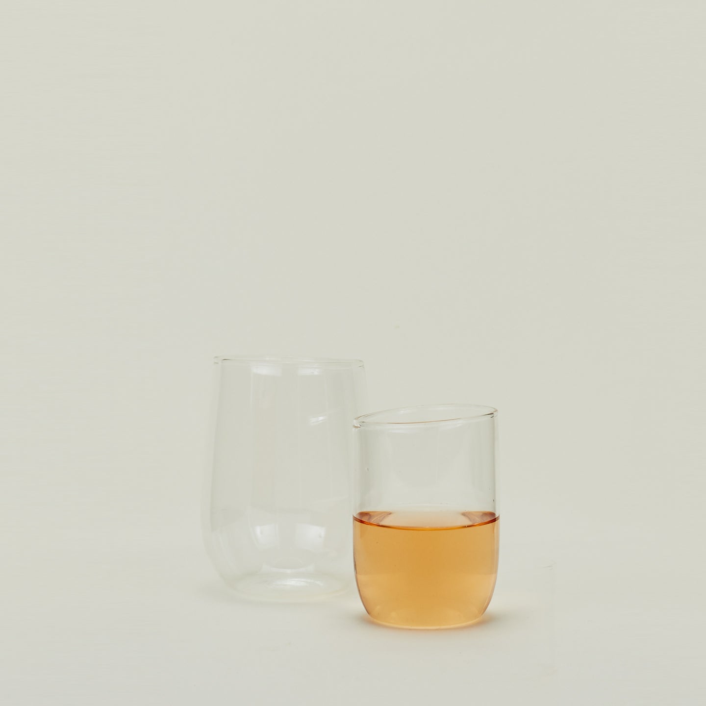 Two clear Boreal Tumblers in various sizes, one filled with sparkling wine.