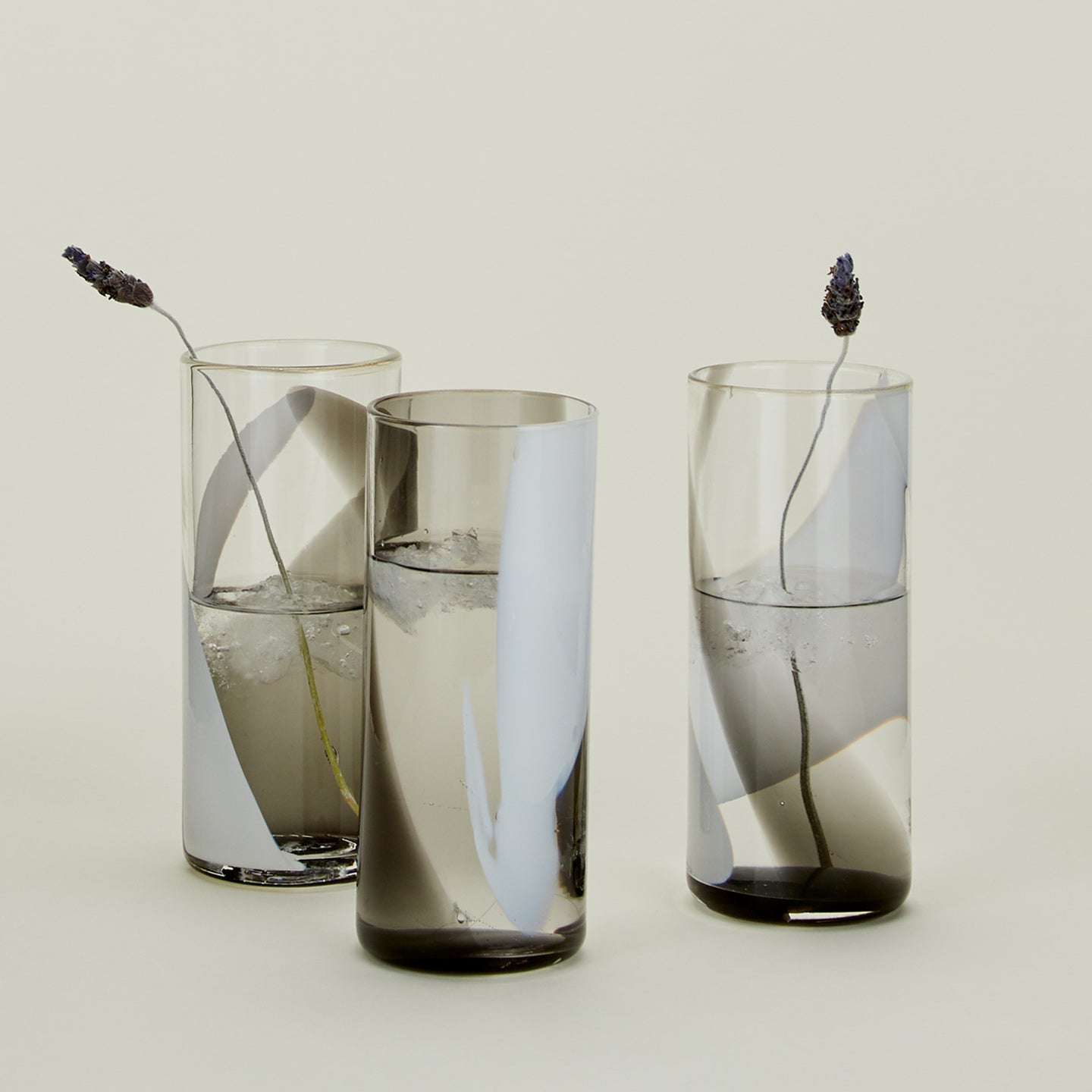 Three Blown Glass Highballs in White and Grey, filled with water and garnished with lavender.