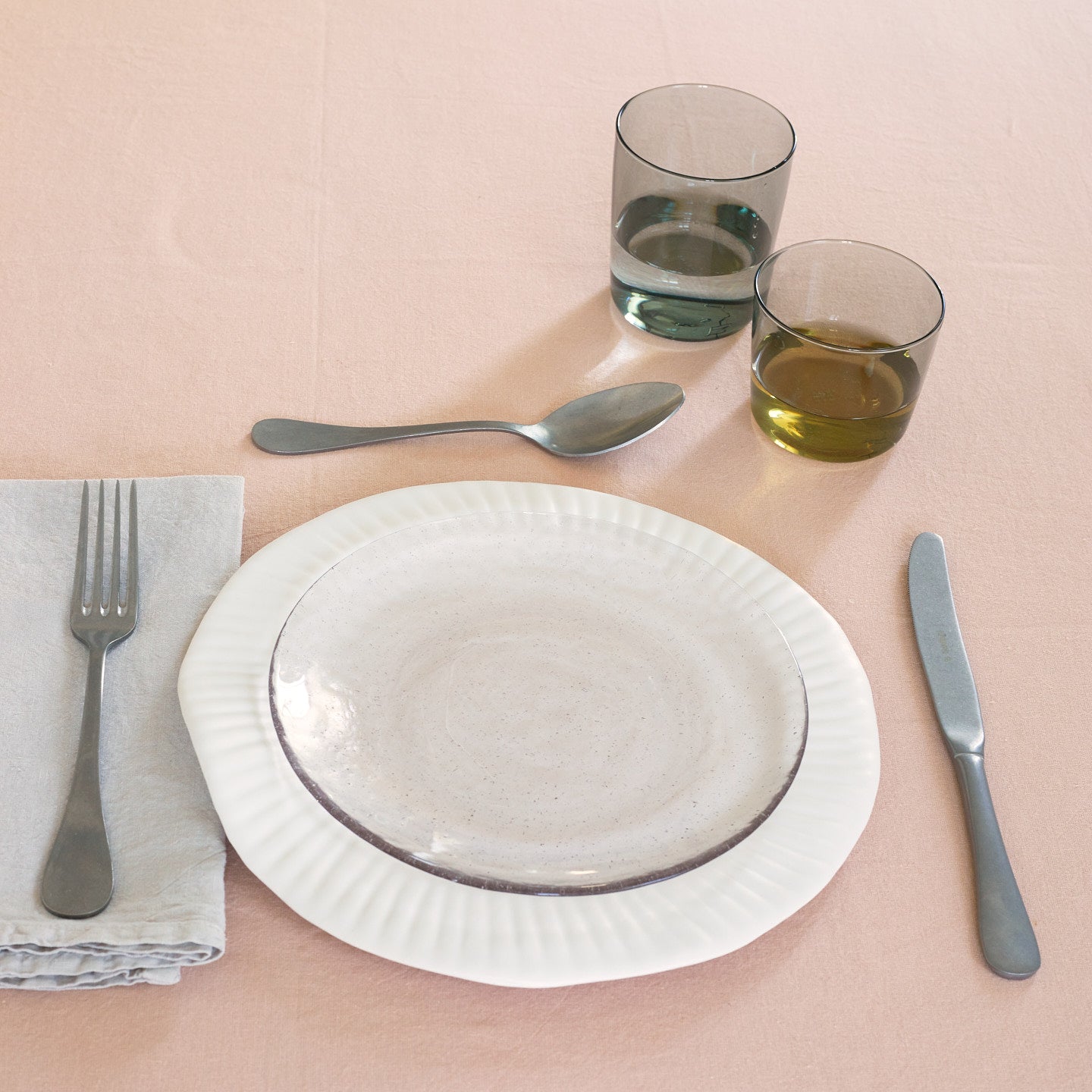 Placesetting with Glass Salad Plate in Blush on pink tablecloth.