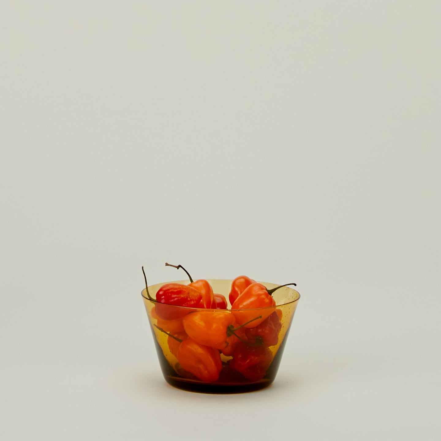 Glass Bowl in Amber, filled with peppers.