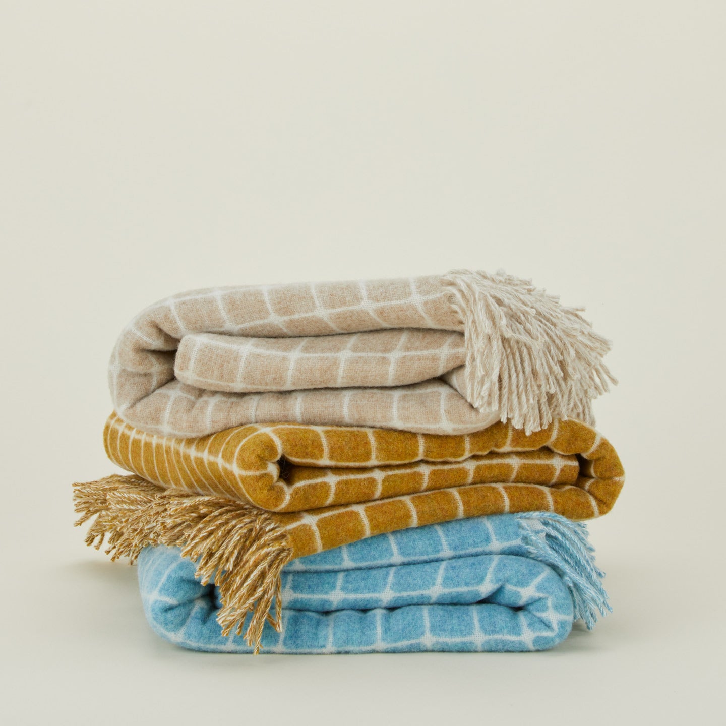 Folded stack of merino wool check throws in various colors. 