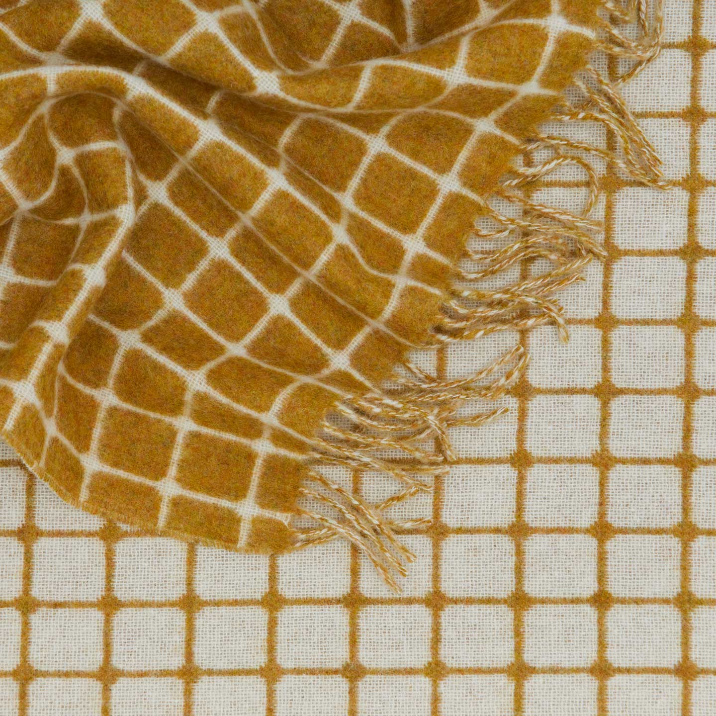 Texture detail of merino wool check throw in mustard.