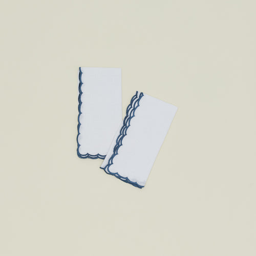 A set of two napkins with a scalloped edge in blue.