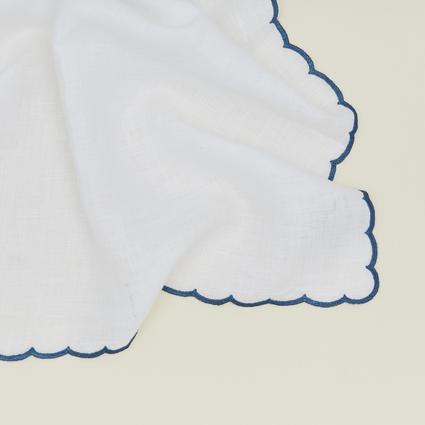 Detail of a napkin with a scalloped edge in blue.