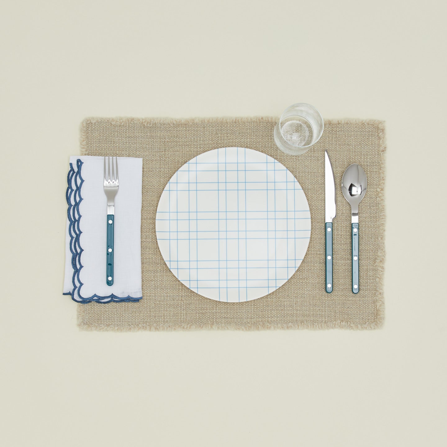 Place setting with a napkin with a scalloped edge in blue.