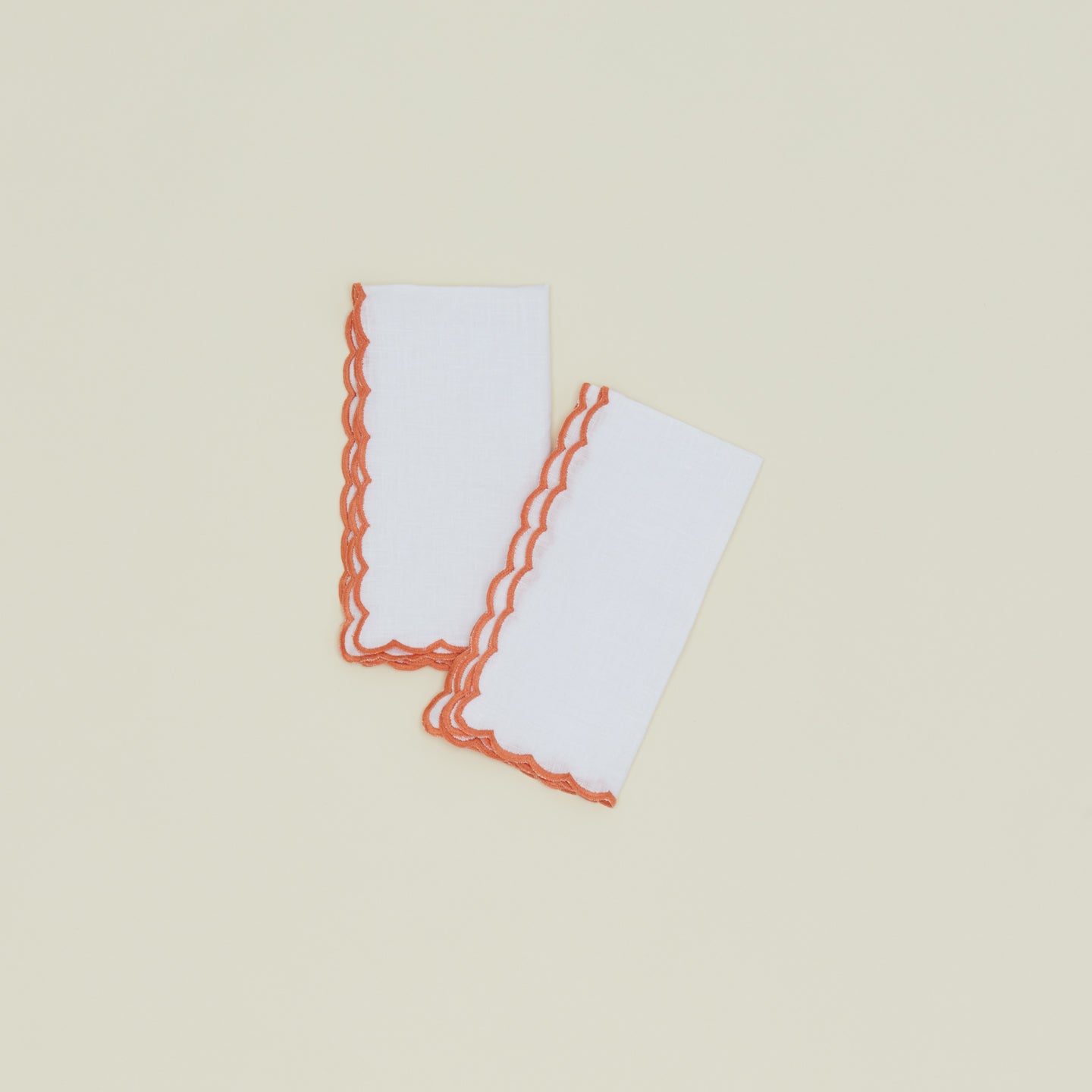 A set of two napkins with a scalloped edge in orange.