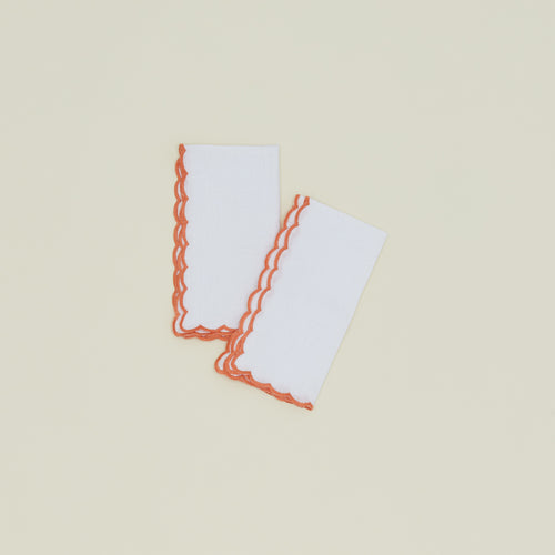 A set of two napkins with a scalloped edge in orange.