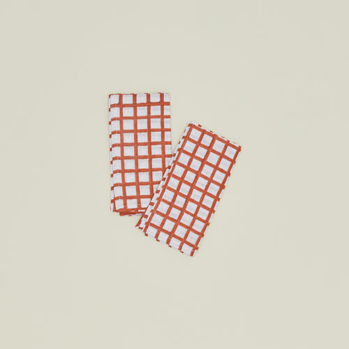 A set of two block printed napkins with a grid pattern in persimmon.