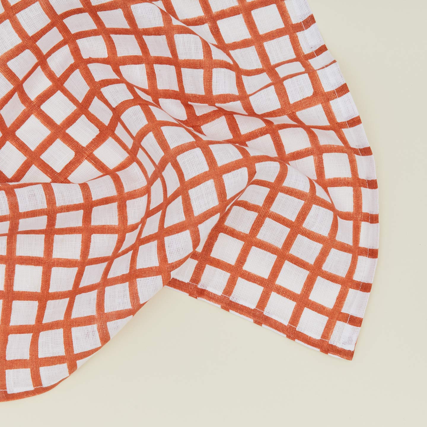 Detail of block printed napkin with a grid pattern in persimmon.