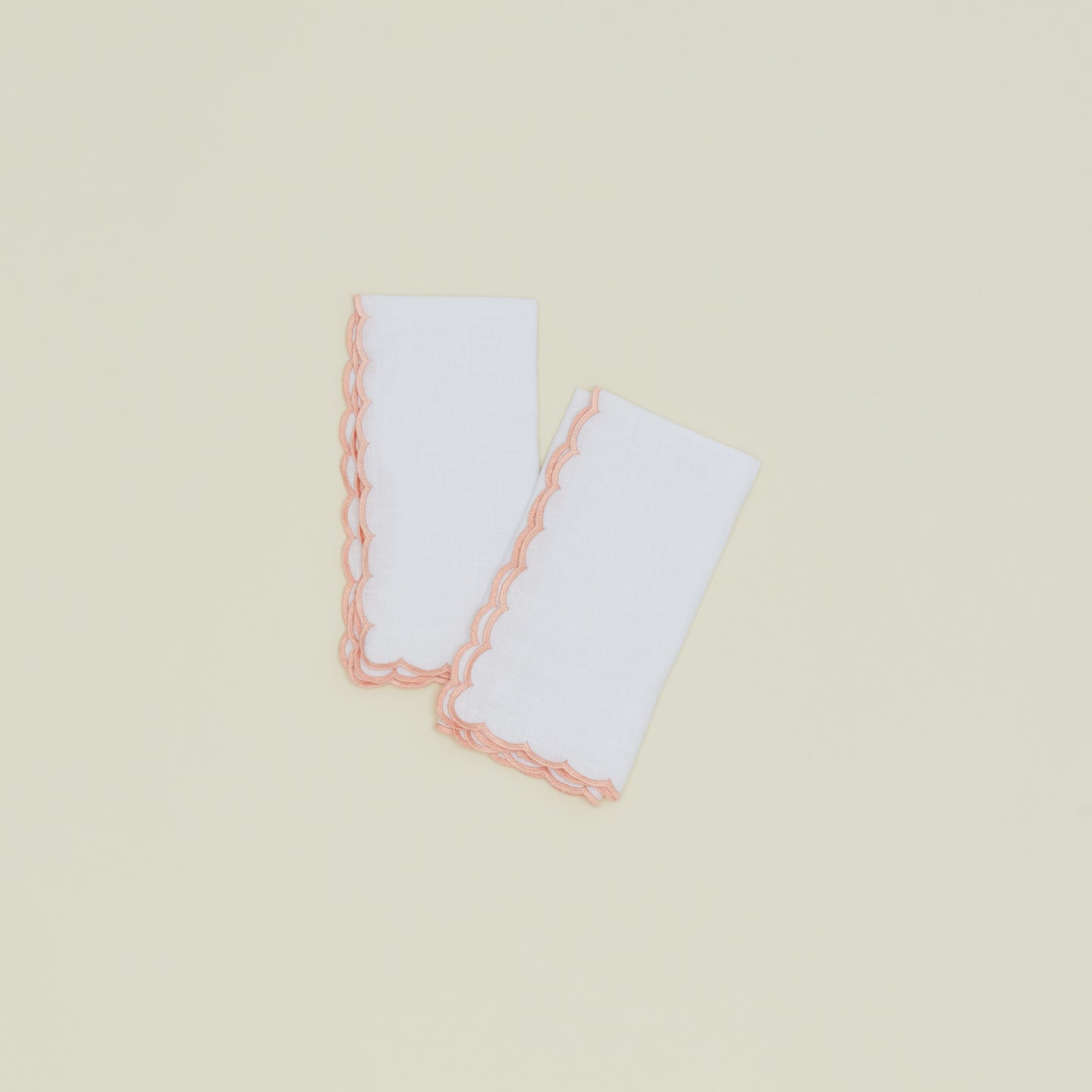 A set of two napkins with a scalloped edge in pink.