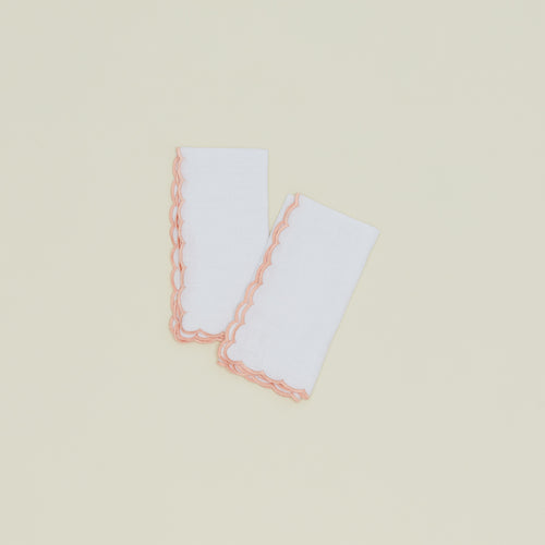 A set of two napkins with a scalloped edge in pink.