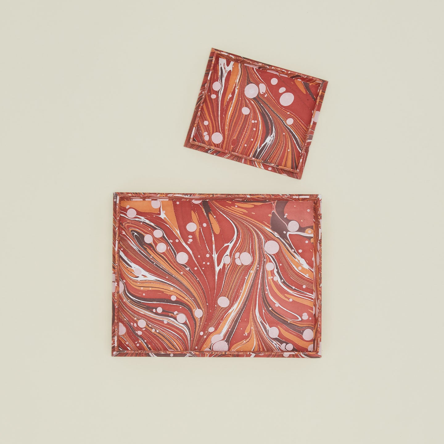 Overhead view of two scalloped marbled trays in red.