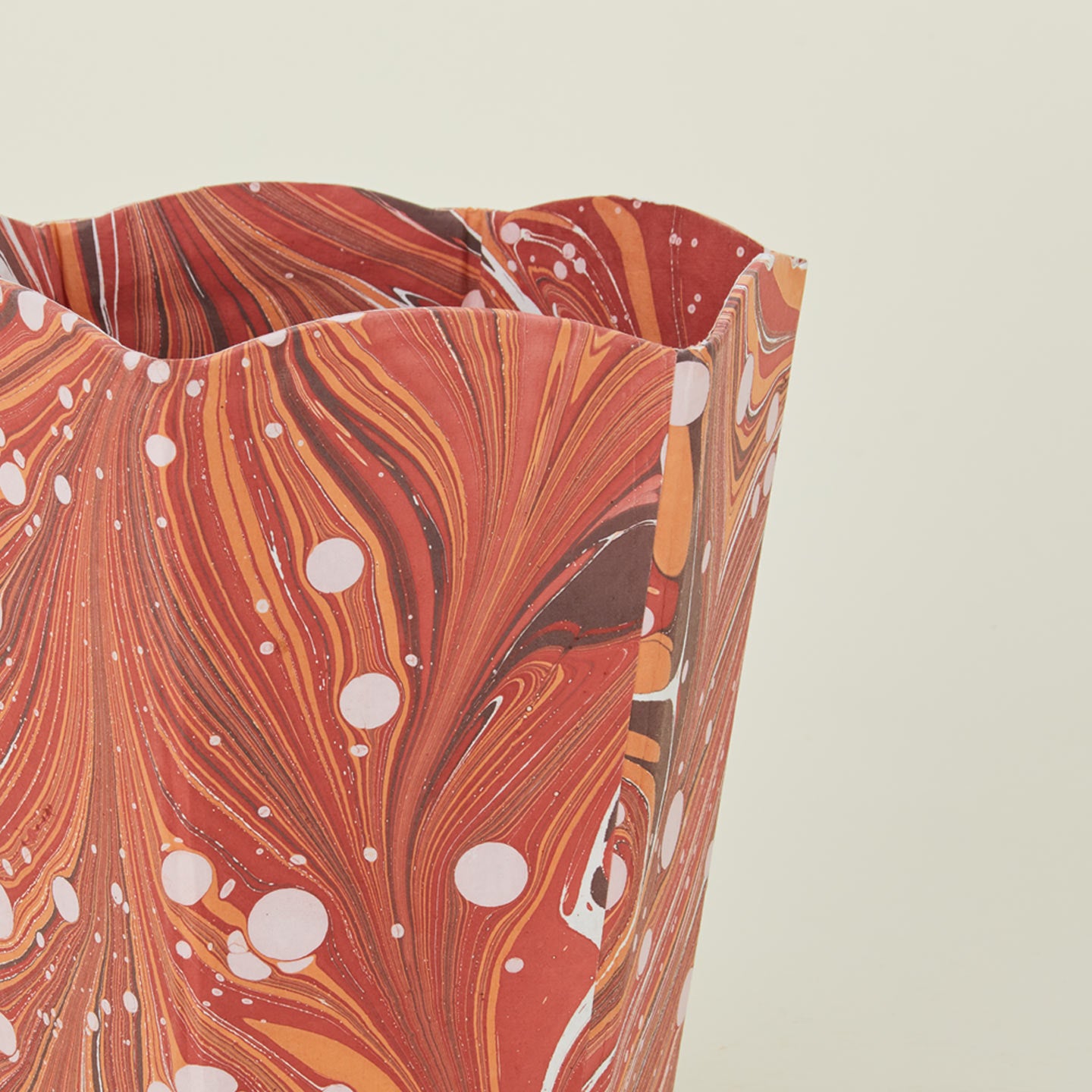 Detail of marbled scalloped wastebasket in red.