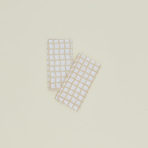 A set of two block printed napkins with a grid pattern in tan.