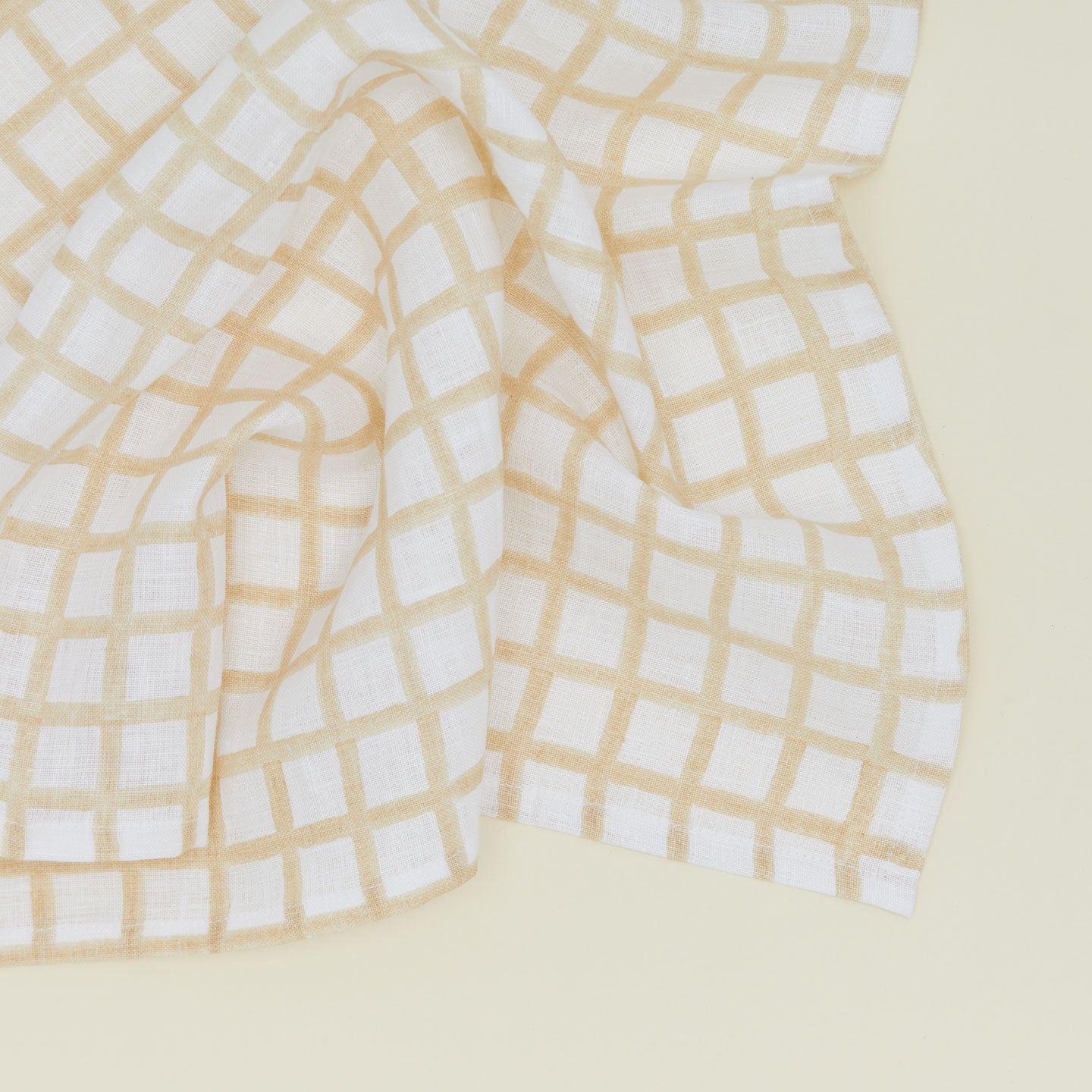 Detail of block printed napkin with a grid pattern in tan.