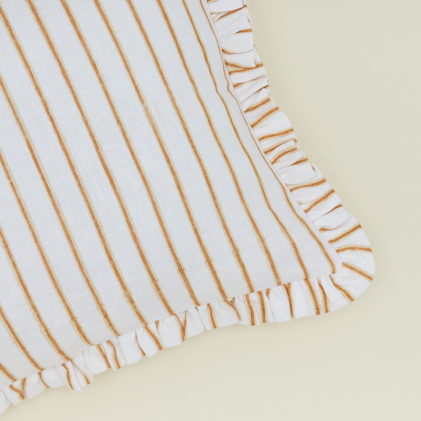 Detail of block printed striped ruffled pillow in Tan.