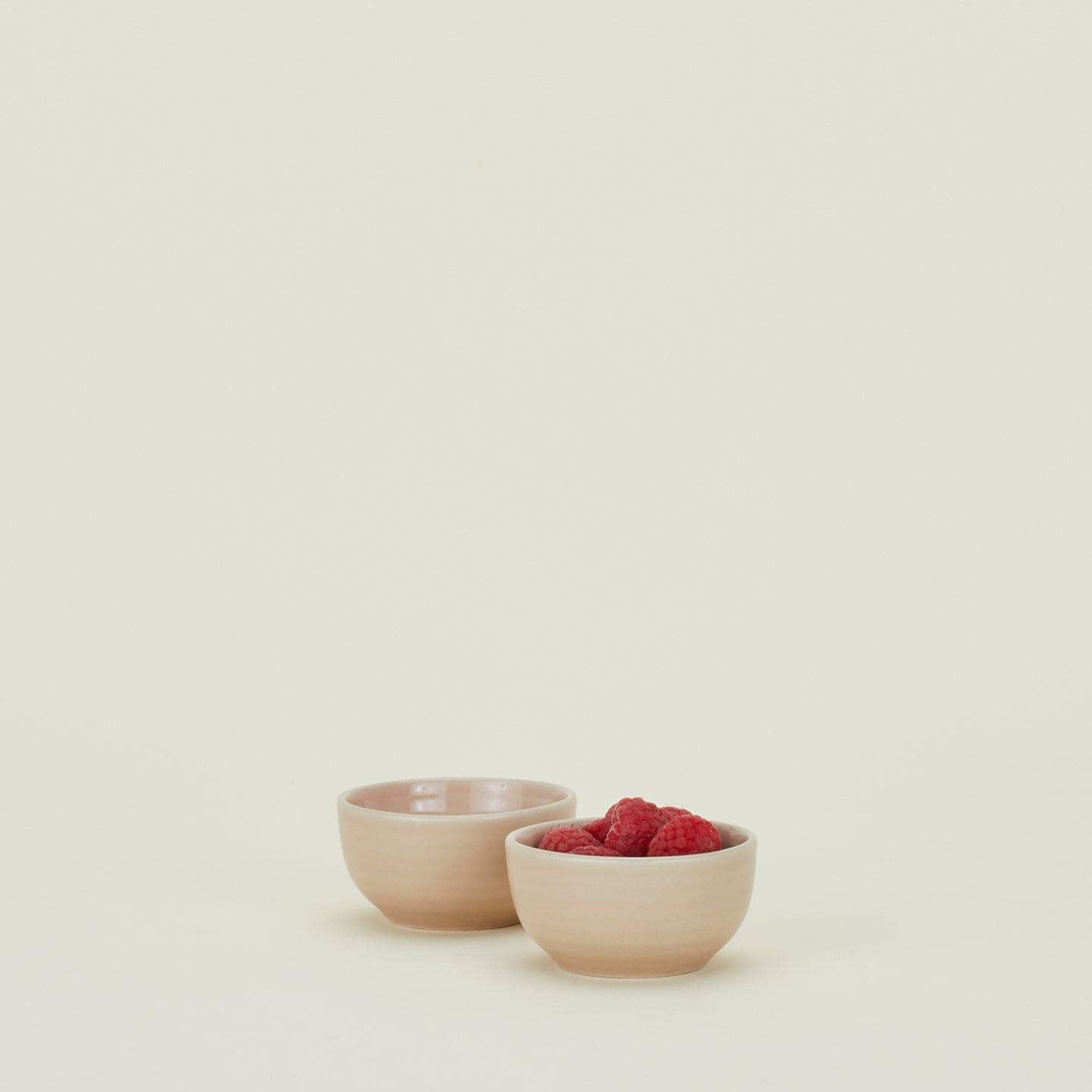 Two Essential Extra Small Bowls in Blush filled with raspberries.