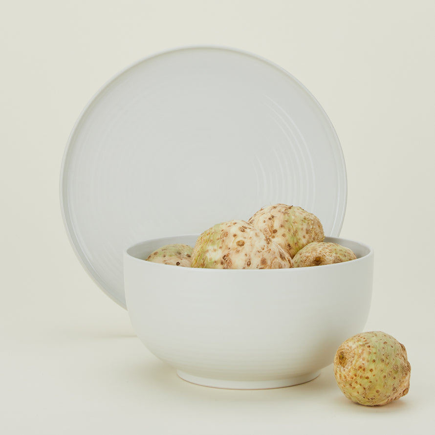 Essential Serving Bowl and Serving Platter in Bone, with root vegetables.