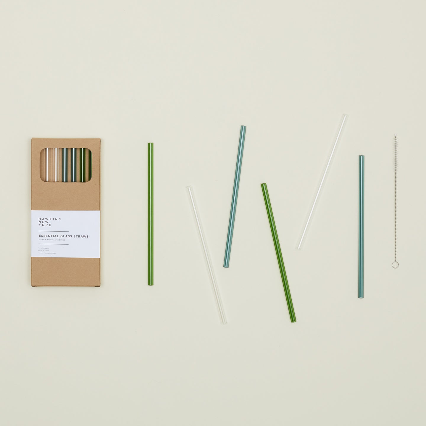 Kraft colored gift box of Essential Glass Straws in Cools, with straws scattered nearby.