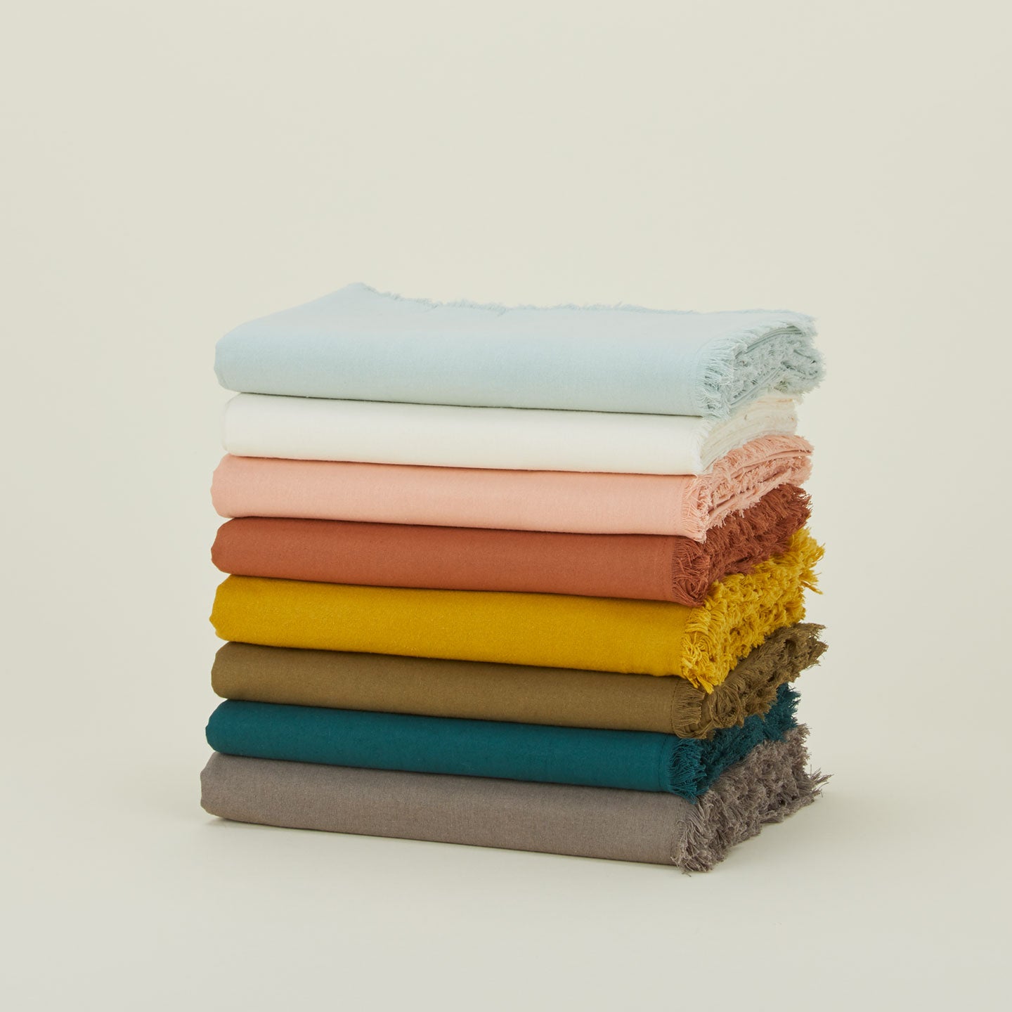 Stack of Essential cotton tablecloths in various colors.
