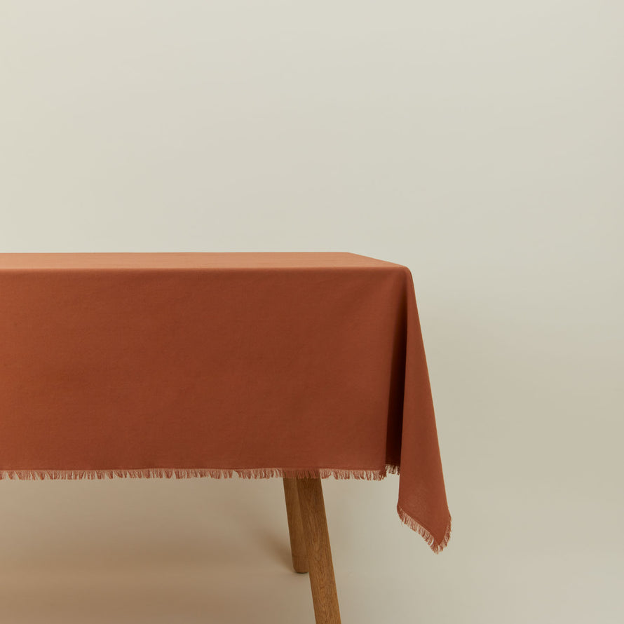 Essential cotton tablecloth in terracotta on table.