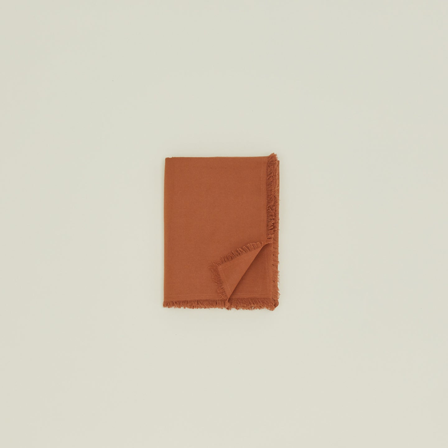 Folded Essential cotton tablecloth in terracotta.