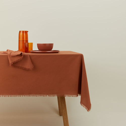 Essential cotton tablecloth in terracotta on table.